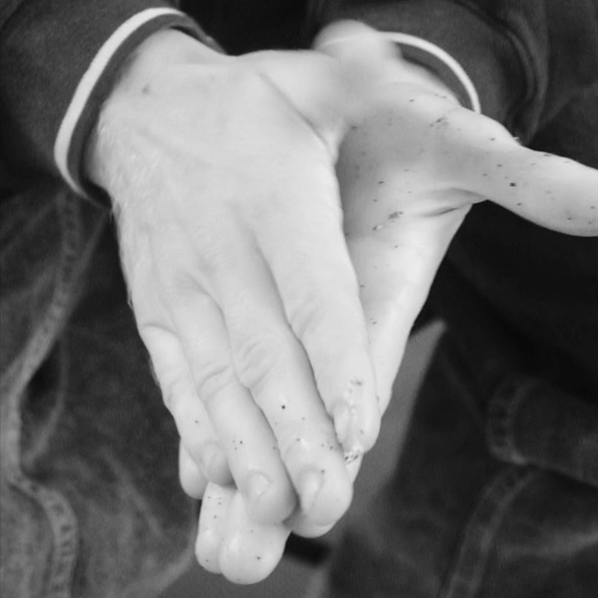 Two hands applying Hard Grit rock climbing cream after a bouldering / climbing session to remove rope grime, grease, grit, dead skin, from hands and condition hands 