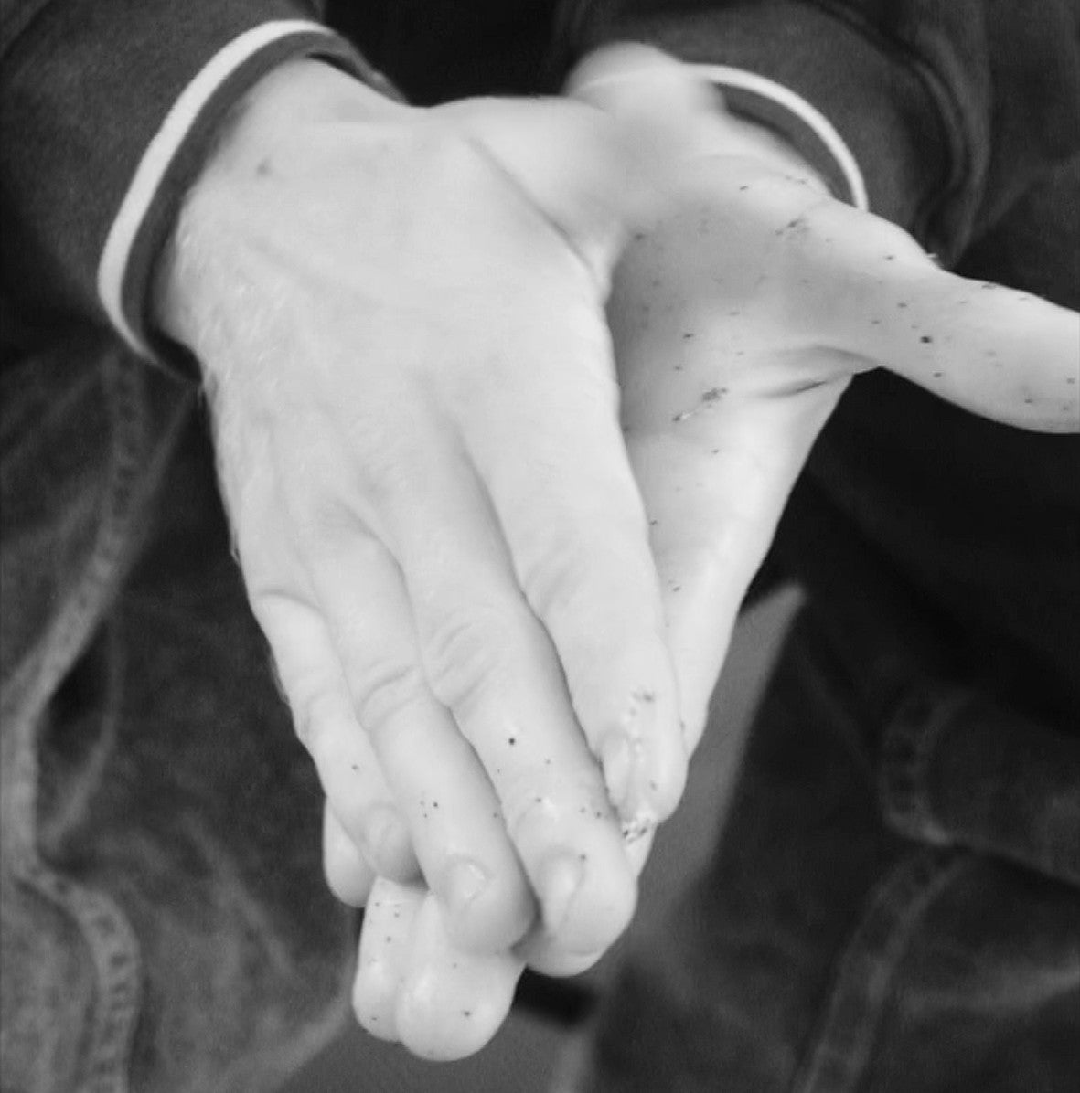 Two hands applying Hard Grit rock climbing cream after a bouldering / climbing session to remove rope grime, grease, grit, dead skin, from hands and condition hands 