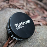 150ml aluminum tin of Tuffenup's Hard Grit rock climbing cream for removing rope grime sitting on a rock.